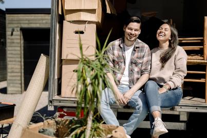 Portrait of happy couple sitting in delivery truck during sunny day